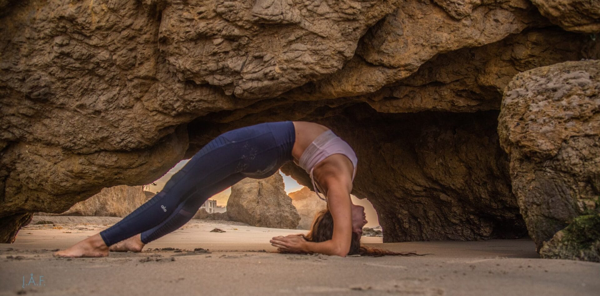 A woman doing a yoga pose on the beach.