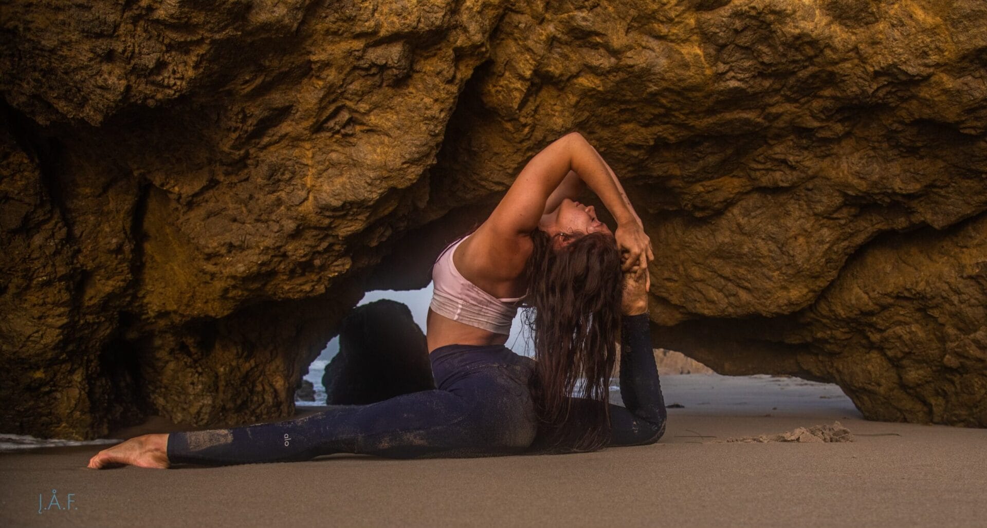 A woman doing yoga in front of a rock.